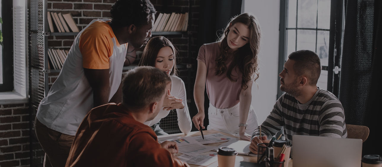 group of people standing around a table having a discussion