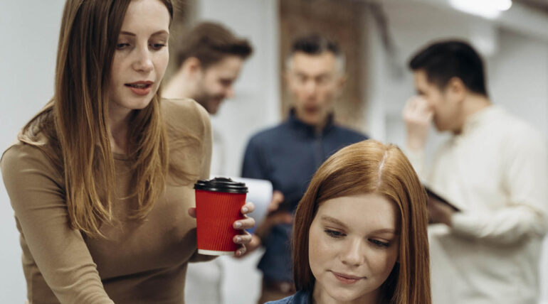 two women talking with a takeaway coffee